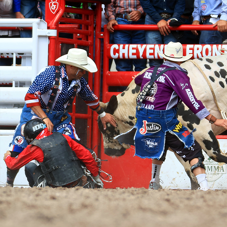 Two rodeo clowns and a bull rider getting out of the way of a bull.